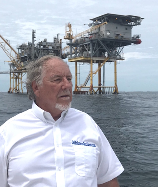 Cpt Ron standing offshore with a production platform in the background