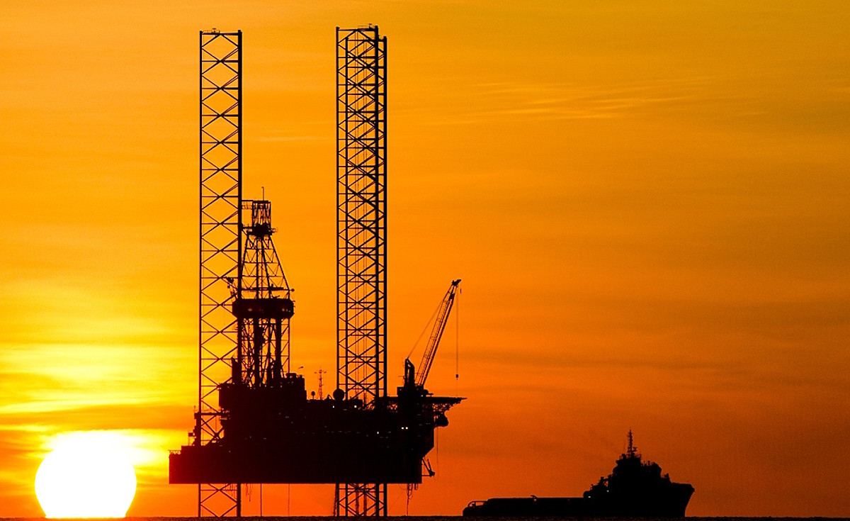 Jack up rig at sunset with an offshore supply vessel alongside