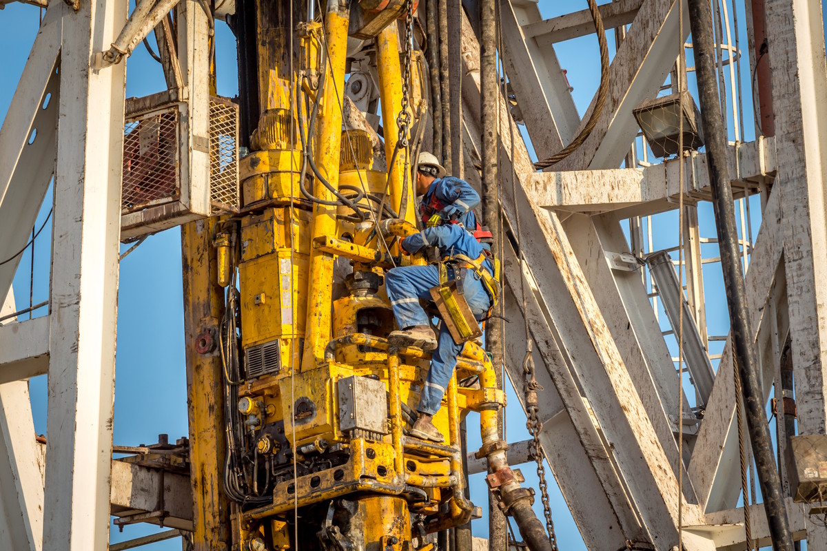 Offshore mechanic working on equipment during maintenance operations, wearing proper PPE and safety gear.