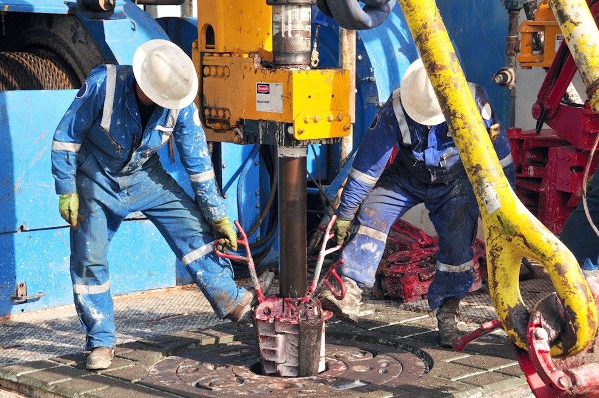 Offshore roughnecks pulling slips on the drill floor during drilling operations